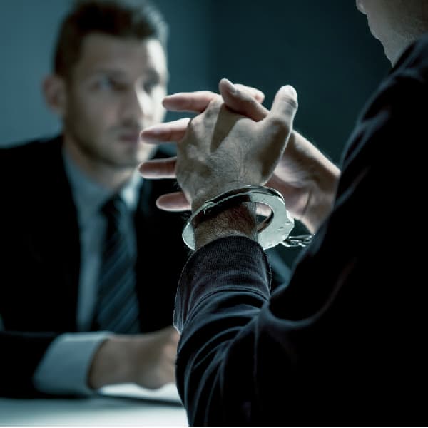 Close-up of a man in handcuffs being interviewed in a police interrogation room
